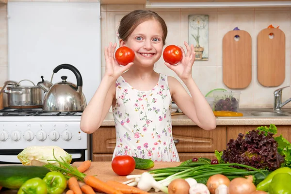 Kind meisje met plezier met tomaten. Huis keuken interieur met groenten en fruit. Gezonde voeding-concept — Stockfoto