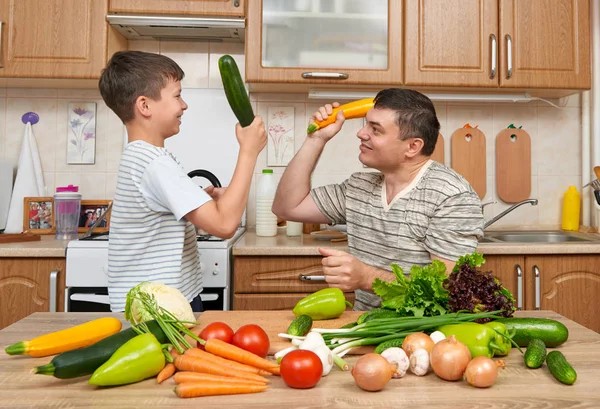 Baba ve oğul eğleniyor ile sebzeler ev mutfak iç. Adam ve çocuk. Meyve ve sebze. Sağlıklı gıda kavramı
