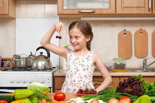 Child girl posing with cherry, fruits and vegetables in home kit — Stock Photo, Image