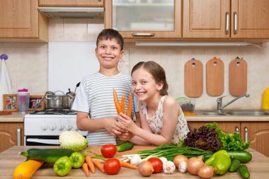 Çocuk kız ve erkek domates ve havuç ile eğleniyor. Ev kiti