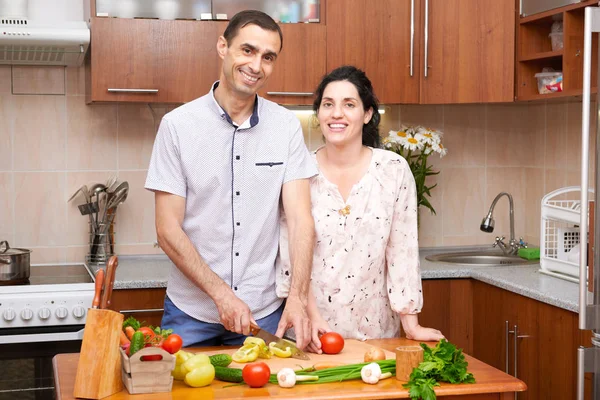 couple cooking in kitchen interior with fresh fruits and vegetables, healthy food concept, pregnant woman and man