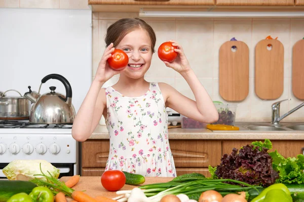 Dítě dívka baví s rajčaty. Domácí kuchyně interiér s — Stock fotografie