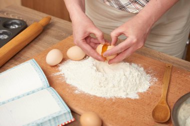 Kadın un bir ahşap arka plan üzerinde pişirme için hazırlanıyor. Çiğ gıda ve mutfak aletleri. El ve gıda portre. Hamur yemek yumurta kırmak.