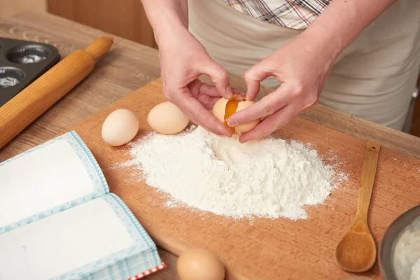 Kadın un bir ahşap arka plan üzerinde pişirme için hazırlanıyor. Çiğ gıda ve mutfak aletleri. El ve gıda portre. Hamur yemek yumurta kırmak.