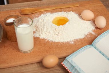 Un ve bir ahşap arka plan üzerinde pişirme için kırık yumurta portre. Çiğ gıda ve mutfak gereçleri.