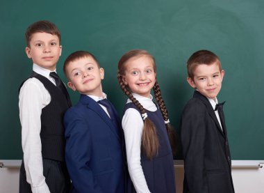 İlköğretim Okulu erkek arkadaş, boş kara tahta arka plan, dalga geçmeyi giyinmiş klasik siyah takım elbise, grup öğrenci, eğitim ve dostluk kavramı