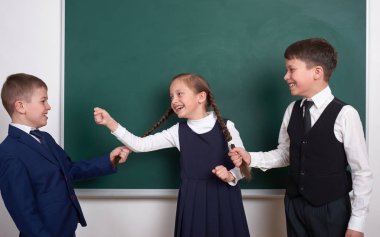 Çocuk oyun ve eğlenmek, çocuklar kız örgüler, boş okul kara tahta arka plan, giyinmiş klasik siyah takım elbise, grup öğrenci, eğitim kavramı yakınındaki çekin.