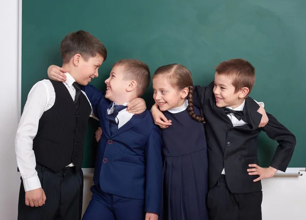 Copains de l'école primaire, s'amuser autour de tableau blanc arrière-plan, habillé en costume noir classique, élève de groupe, concept d'éducation et d'amitié — Photo