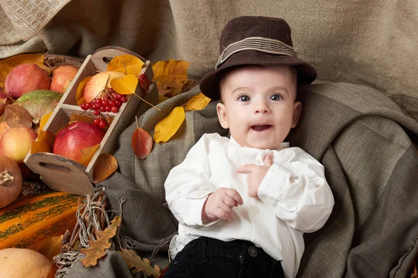 Autumn season, child boy lie on yellow fall leaves, apples, pumpkin and decoration on textile — Stock Photo, Image