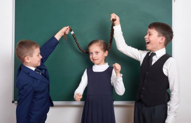 Çocuk oyun ve eğlenmek, çocuklar kız örgüler, boş okul kara tahta arka plan, giyinmiş klasik siyah takım elbise, grup öğrenci, eğitim kavramı yakınındaki çekin.