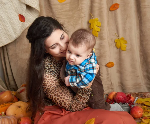 Retrato familiar en temporada de otoño. Mujer y niño se sientan en hojas de otoño amarillo, manzanas, calabaza y decoración —  Fotos de Stock