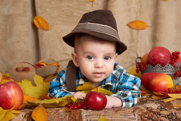 Kind liegt auf gelben Herbstblättern, Äpfeln, Kürbis und Deko, Herbstzeit — Stockfoto