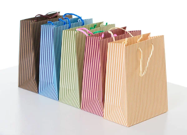 Coloridas bolsas de compras a rayas dispuestas en una fila, objeto aislado en blanco — Foto de Stock