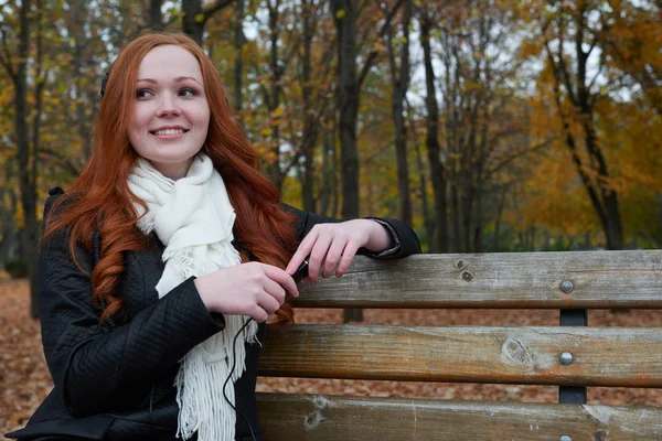 Giovane donna ritratto nel parco autunnale, ascoltando musica con le cuffie — Foto Stock