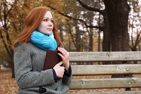 Kızıl saçlı kız sonbahar park kitap ile sarı yapraklar ve ağaçlar