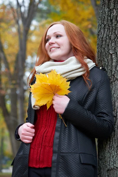 Junge Frau steht neben Baum im Herbstpark, gelbe Blätter — Stockfoto