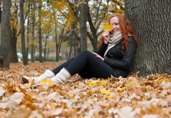 Ung kvinna sitta nära träd i park och läsa bok, gula höstlöv — Stockfoto