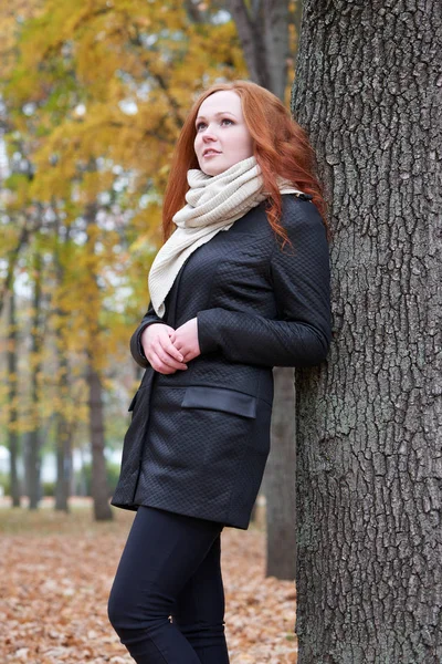 Ung kvinna stå nära träd i parken, gula höstlöv — Stockfoto
