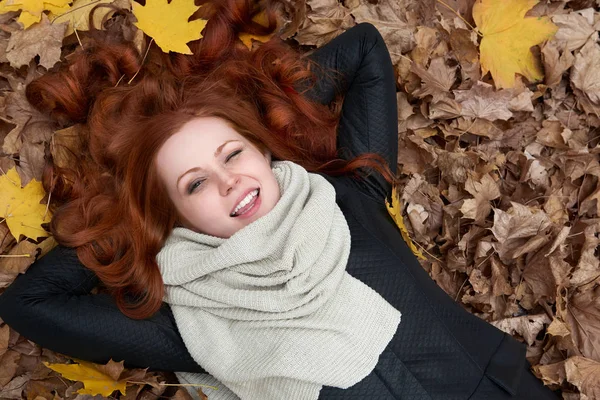 Girl lie on autumn leaves background in city park — Stock Photo, Image