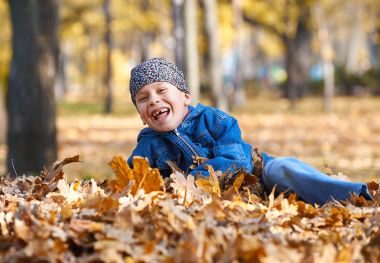 Çocuk yalan sonbahar park, parlak güneşli bir günde, zemin üzerine düşen yapraklar sarı yapraklarda