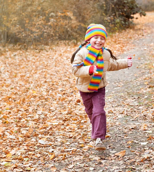Child girl runs on a path in forest, autumn leaves background, fall season — Stock Photo, Image