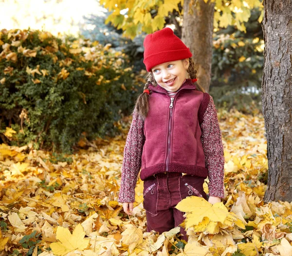 Tjej att ha kul en göra ansikten i höst skog, gula blad och träd på bakgrund — Stockfoto