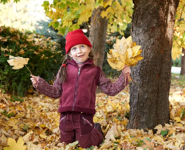 Meisje met plezier een make gezichten in herfst bos, gele bladeren en bomen op de achtergrond — Stockfoto