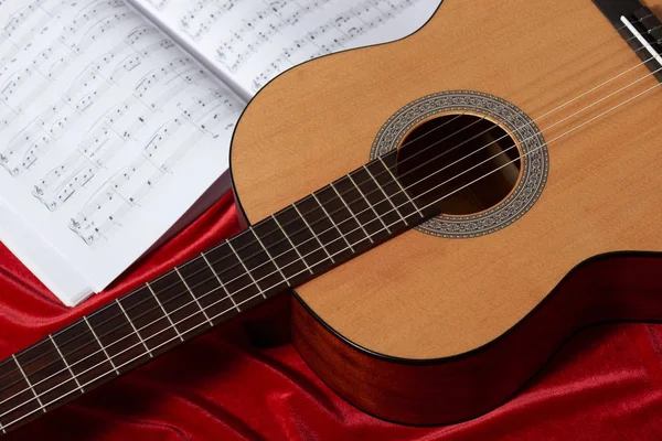 acoustic guitar and music notes on red fabric, close view of obj