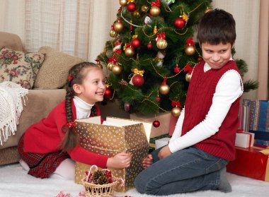 Eğleniyor ve oynarken, hediyeler, Noel dekorasyonu evde, mutlu duygu, kış tatil kavramı paylaşımı santa şapkalı çocuk