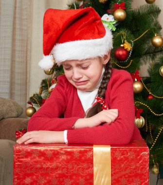 Mutsuz kız Noel ağacı, giymiş kırmızı ve santa şapka yakınındaki gözyaşı