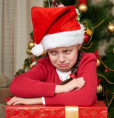 Noel ağacı, giymiş kırmızı ve santa şapka ağlama mutsuz kız