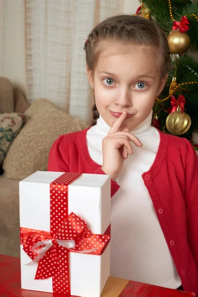 Girl thinks about a gift near christmas tree, happy holiday and winter celebration