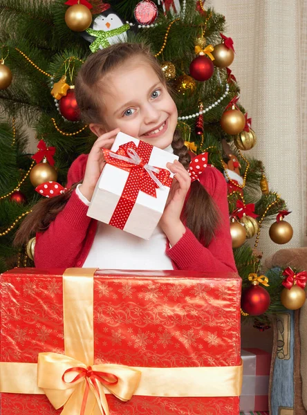 Mädchen in der Nähe von Weihnachtsbaum und Geschenkschachteln, frohe Feiertage und Winterfeste, in rot gekleidet Stockfoto
