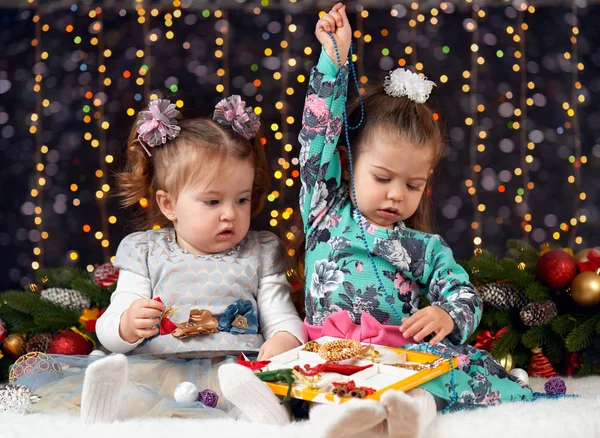 Две девушки открывают подарочные коробки в рождественском оформлении, темный фон с освещением и бокс-огни, концепция зимнего отдыха — стоковое фото