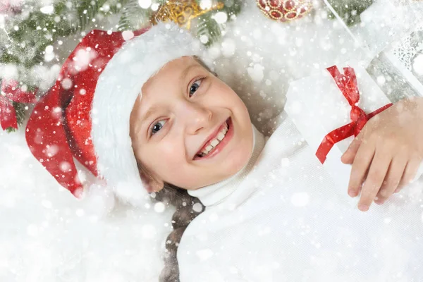 Niña de mentira en la decoración de Navidad en piel blanca, primer plano de la cara, vestido con sombrero de santa, concepto de vacaciones de invierno, árbol de Navidad — Foto de Stock