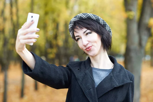 Selfie de uma menina no parque da cidade do outono, folhas e árvores amarelas, estação do outono — Fotografia de Stock