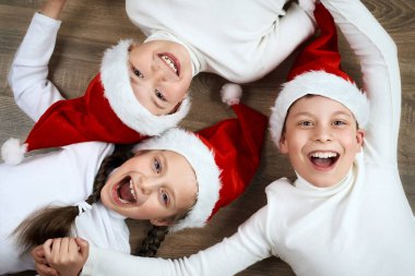 mutlu çocuk yan yana ahşap arka plan üzerinde yatarken giyinmiş christmas Santa şapka ve sahip eğlenceli, kış tatil kavramı
