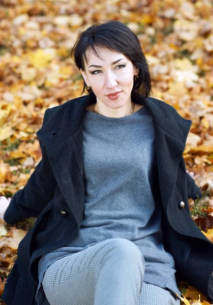 여자는 노란색에 검은 코트에 나뭇잎가 도시 공원에서가 시즌 — 스톡 사진