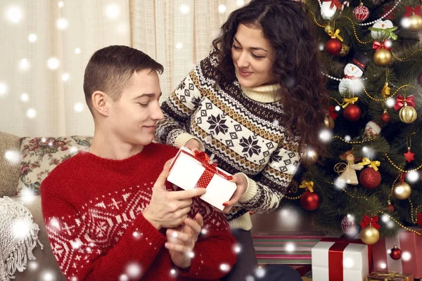Coppia felice dare regali nella decorazione di Natale a casa. Vigilia di anno nuovo, abete ornato. Vacanza invernale e concetto di amore . — Foto Stock