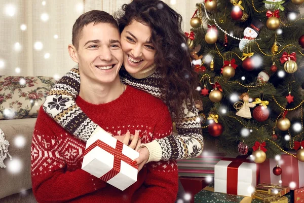Ευτυχισμένο ζευγάρι δίνουν δώρα στη χριστουγεννιάτικη διακόσμηση στο σπίτι. Πρωτοχρονιάς, διακοσμημένους έλατο. Χειμερινές διακοπές και την αγάπη έννοια. — Φωτογραφία Αρχείου