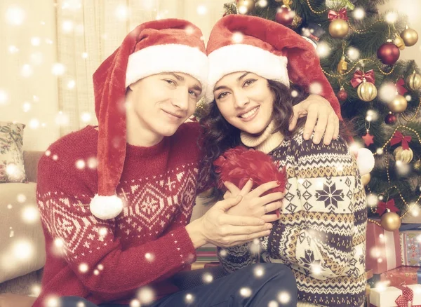 Šťastný pár objetí poblíž vánoční strom a výzdoba doma. Zimní dovolená a lásku koncept. Žlutá tónovat sněhu. — Stock fotografie