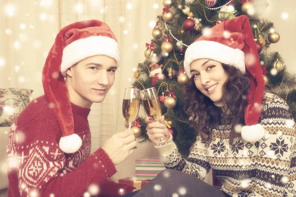 Šťastný pár se vánoční strom a sklenku šampaňského doma. Zimní dovolená a lásku koncept. Žlutá tónovat sněhu. — Stock fotografie
