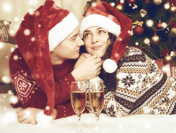 Coppia felice con champagne si trovano vicino all'albero di Natale e decorazione a casa. Vacanza invernale e concetto di amore. Tonica gialla . — Foto Stock