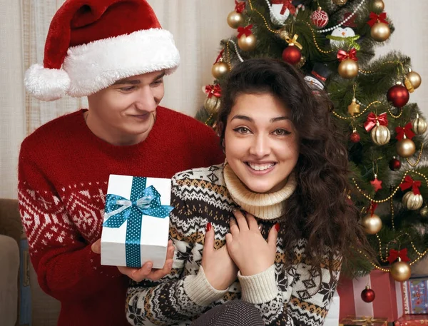 年轻夫妇连同圣诞树和礼物在家庭内部-爱和假日概念, 圣诞节前夕 — 图库照片