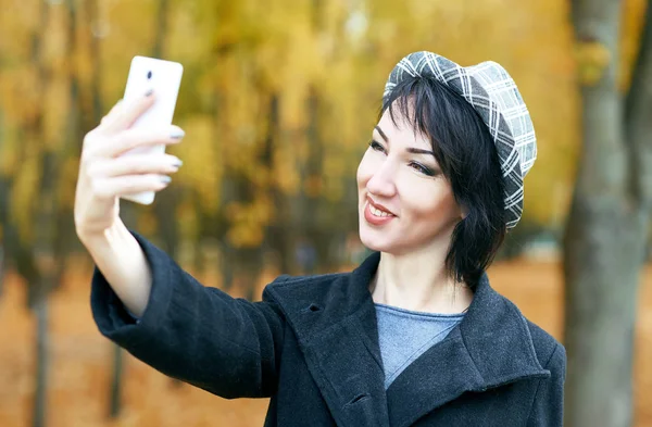 Girl figyelembe fotó őszi városi park, a sárga levelek és a fák, a telefon tartozik szezon — Stock Fotó