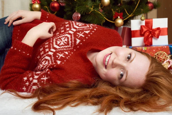 Beautiful girl lie in christmas decoration. Home interior, fir tree and gifts. New year eve and winter holiday concept. — Stock Photo, Image