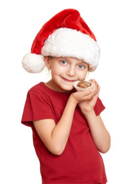 Çocuk beyaz arka plan üzerinde izole çerezler ile santa şapka giymiş. Yeni yıl arifesi ve kış tatil kavramı.