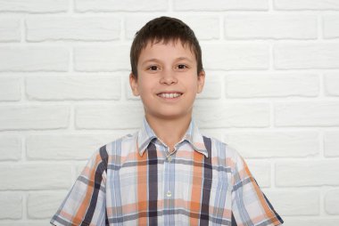 Beyaz tuğla duvara yakın duran bir çocuk portresi giyinmiş bir p