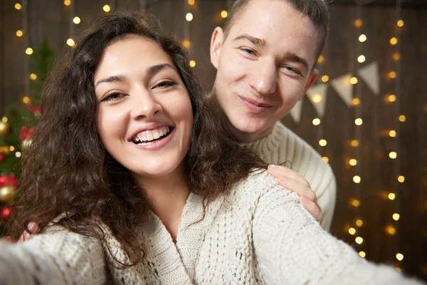 幸福的情侣采取自拍和乐趣在圣诞节装饰。深色木制室内灯。浪漫的夜晚和爱情的概念。新年假期. — 图库照片