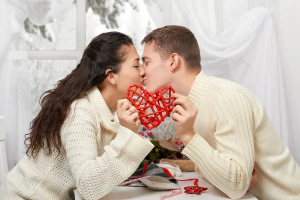 Giovane coppia bacio e mostra un cuore rosso, persone felici - romantico e concetto di amore — Foto Stock